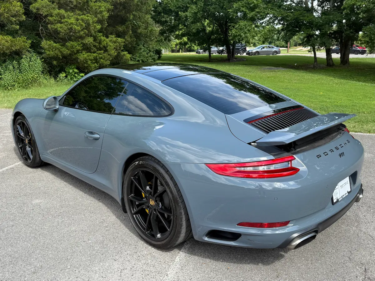 Rear view of a blue-gray 2017 Porsche 911 Carrera with its spoiler raised