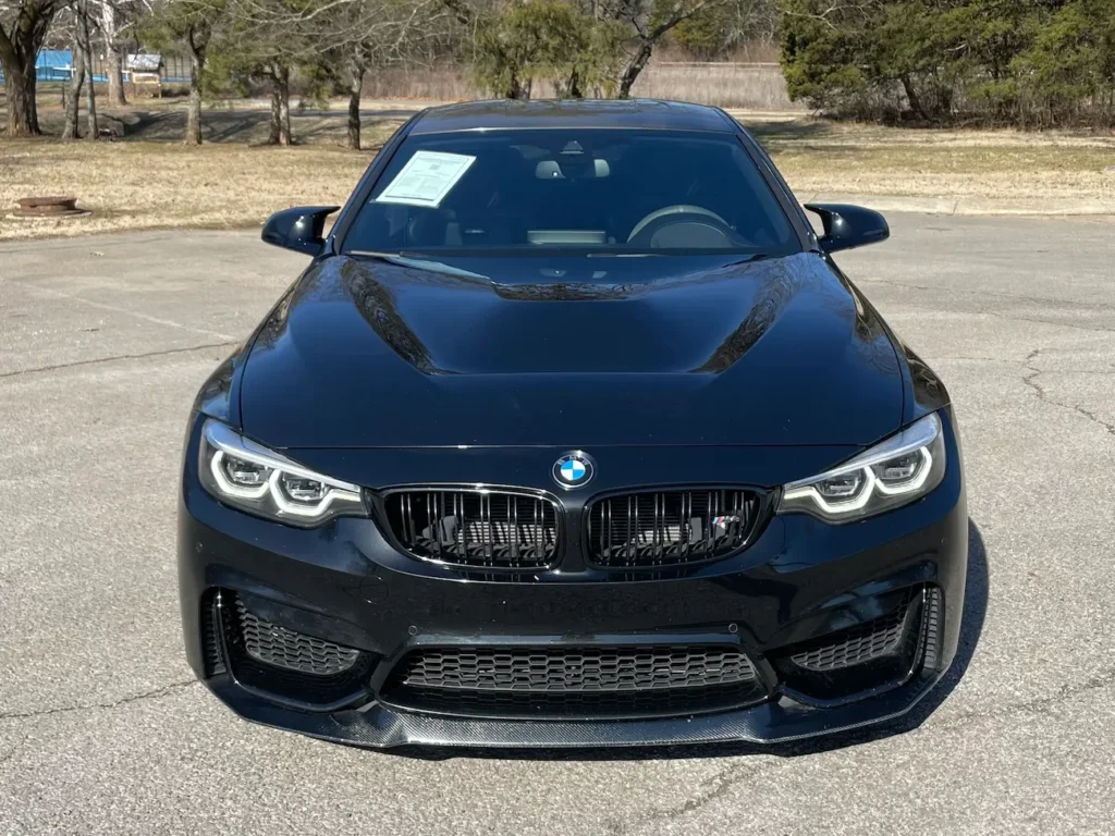 Front view of the 2019 BMW M4 CS black coupe highlighting its kidney grille, LED headlights, and carbon front lip.