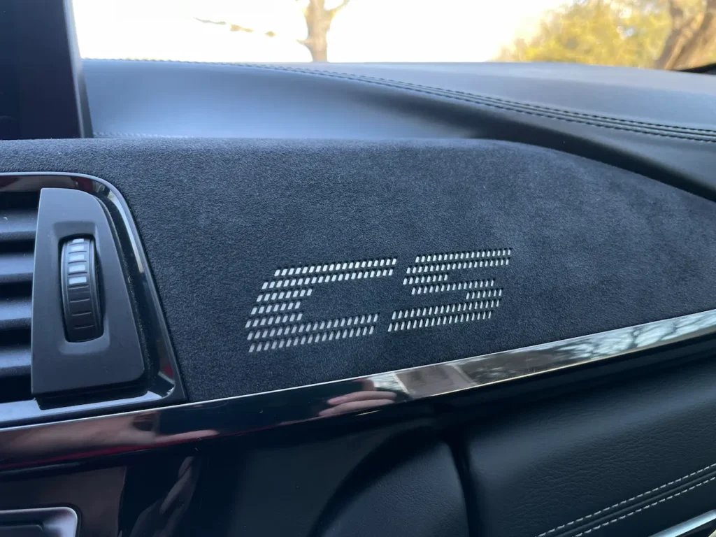 Dashboard detail of the 2019 BMW M4 CS showing Alcantara trim with perforated CS logo.