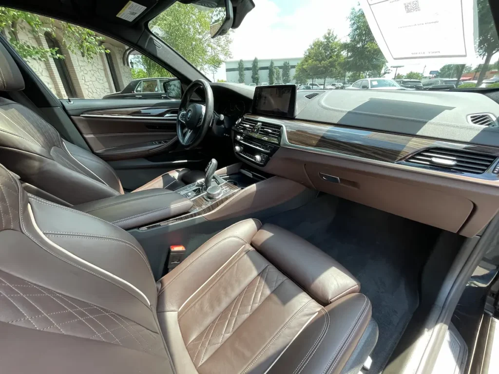 BMW M550i interior front seats with brown leather and wood-grain trim.