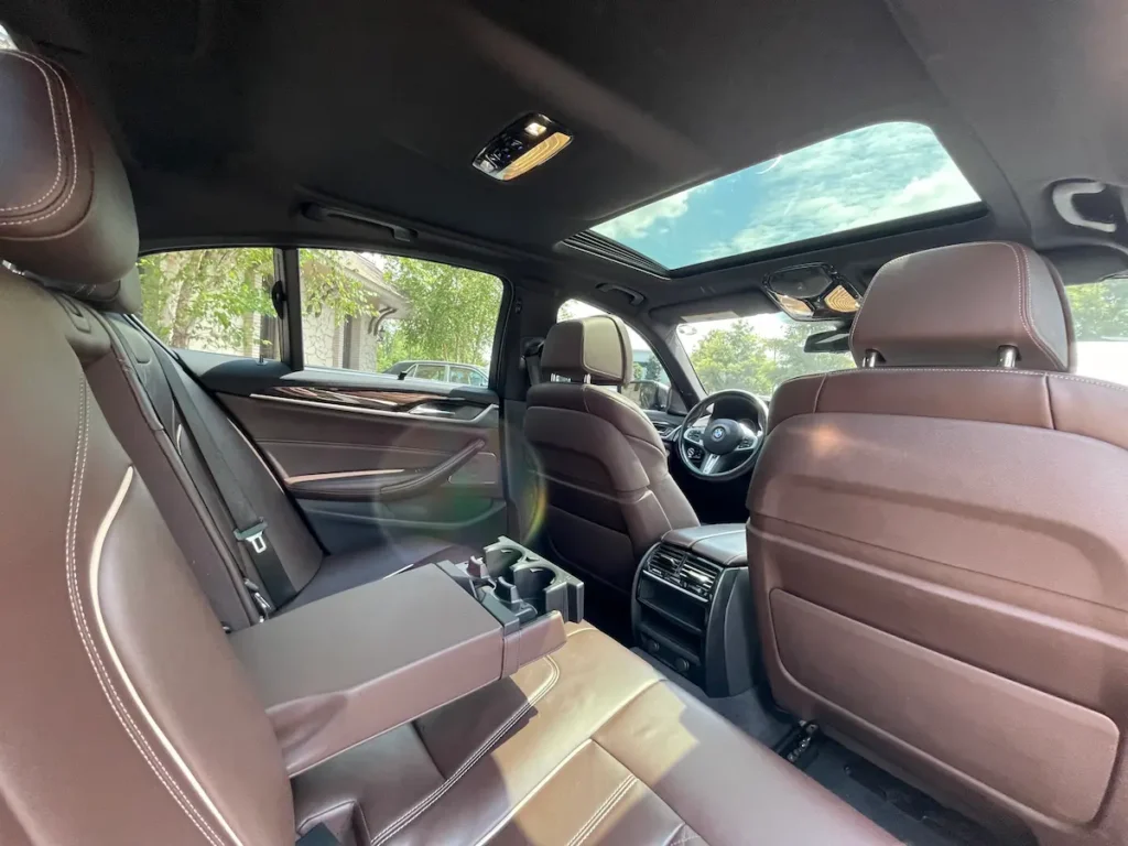 Rear seat interior of BMW M550i xDrive with premium brown leather and ample legroom.