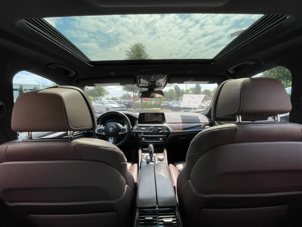 BMW M550i xDrive panoramic sunroof and front dash view from rear seats.