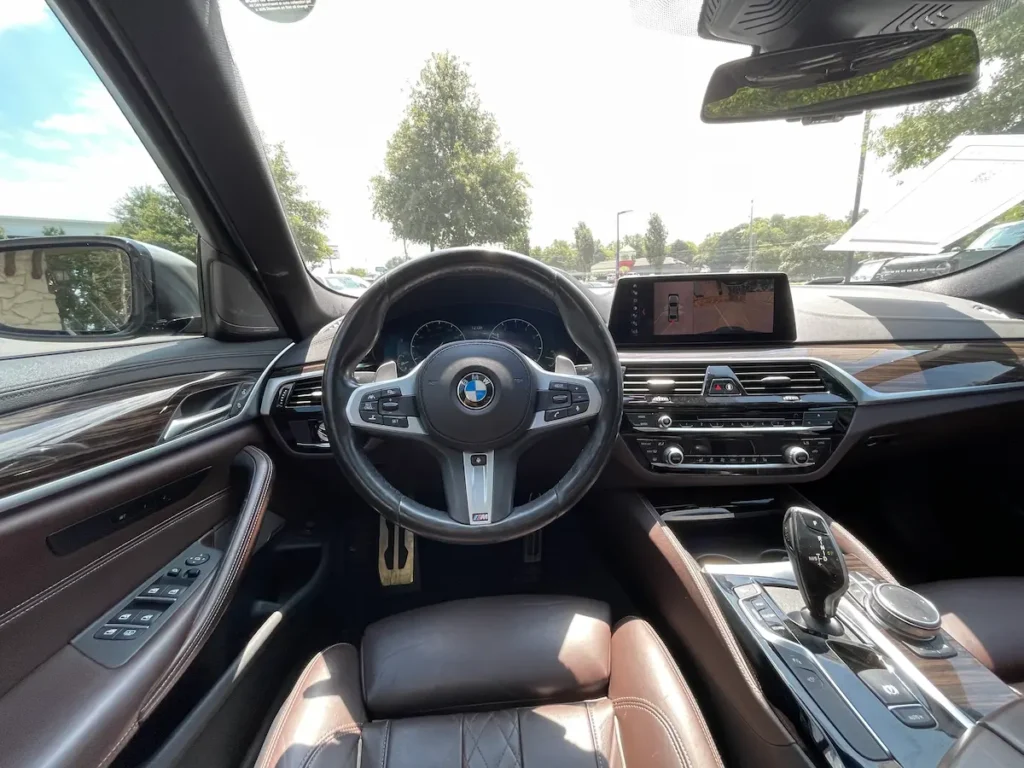 Driver’s cockpit of BMW M550i xDrive featuring M Sport steering wheel and iDrive display.