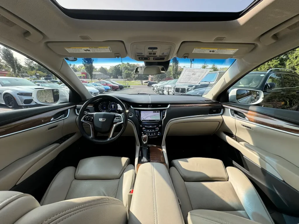 Front interior view of a 2019 Cadillac XTS with premium leather seats and wood trim.