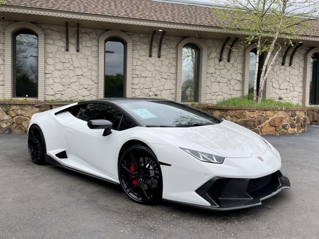  A stunning white 2019 Lamborghini Huracán Performante, a high-performance sports car with signature scissor doors, is displayed in the showroom at AutoPro Nashville, a used car dealership.