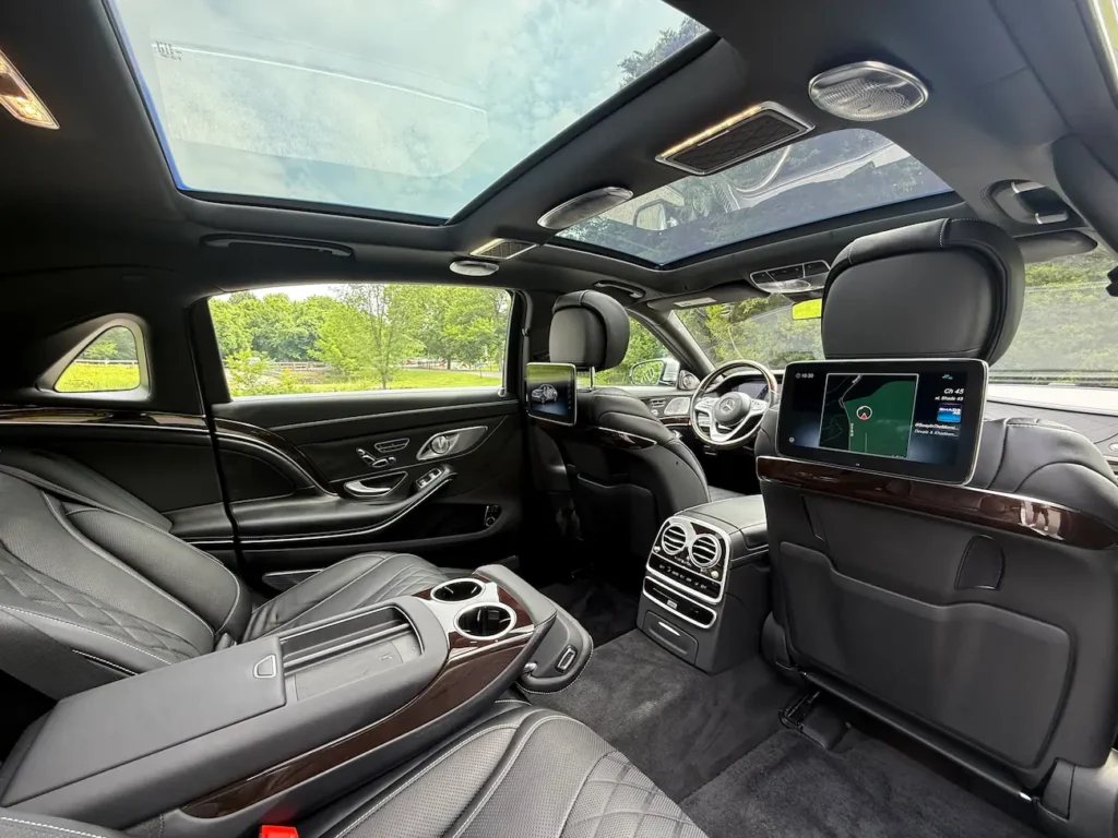 Rear interior of 2019 Mercedes-Benz S560 Maybach featuring dual entertainment screens and panoramic roof.