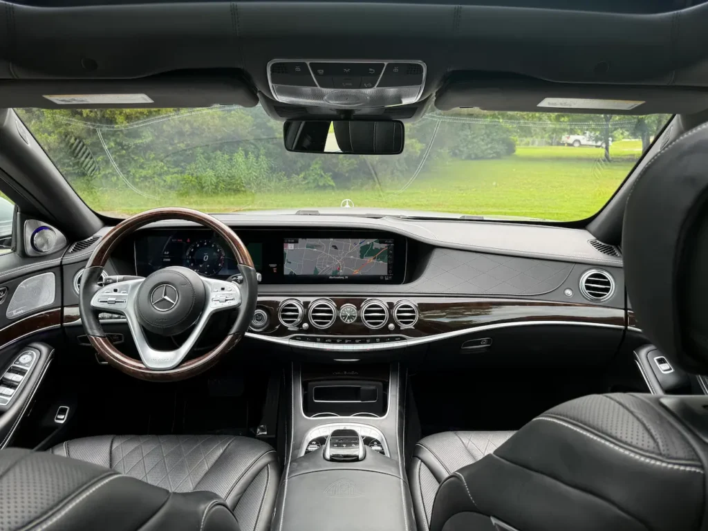 2019 Mercedes-Benz S560 Maybach interior with leather seating, wood trim, and widescreen display.