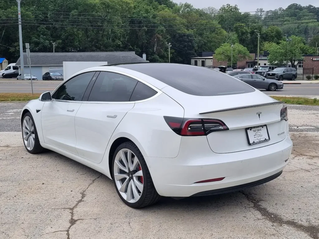 2019 Tesla Model 3 rear three-quarter view emphasizing fastback design, glass roof, and taillights.