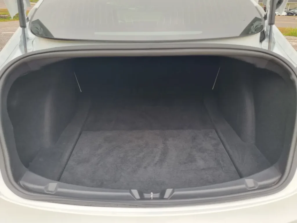 Tesla Model 3 open trunk showing spacious carpeted cargo area with flat load floor.