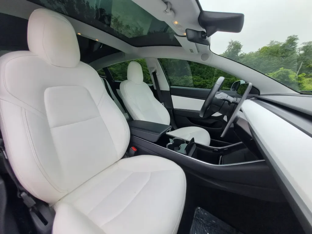 Tesla Model 3 white vegan-leather front seats under panoramic glass roof.