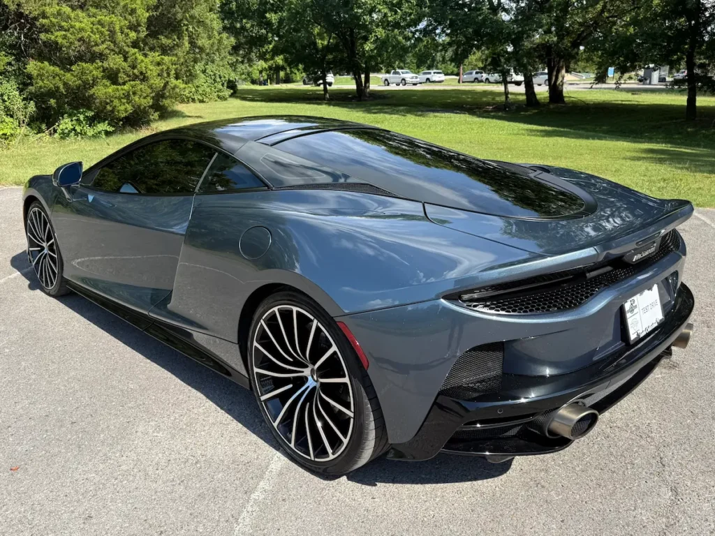 Rear three-quarter view of a 2020 McLaren GT highlighting its sleek bodywork, twin exhaust outlets, and sculpted aerodynamic design.