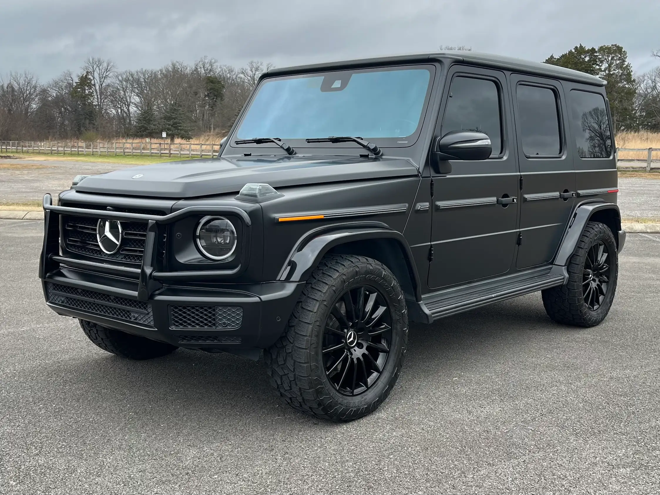 Black 2020 Mercedes-Benz G 550 in front three-quarter view, showing round headlights, black wheels and running boards.