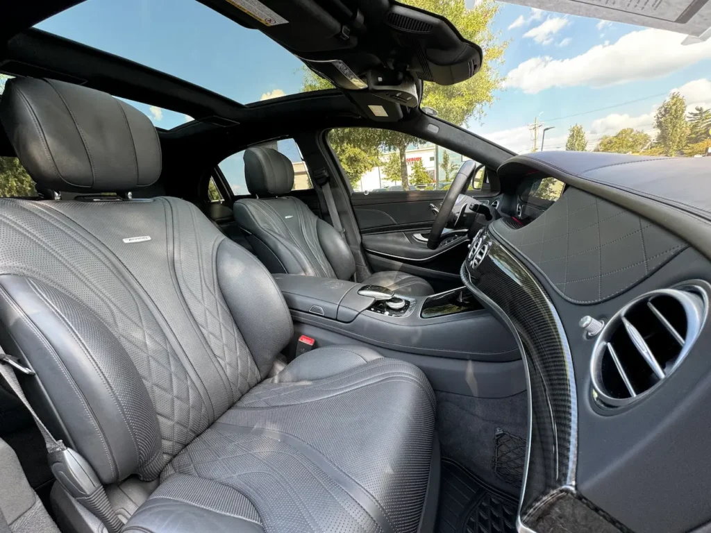 2020 Mercedes-Benz S63 AMG front interior with black leather seats, carbon trim, and panoramic roof.