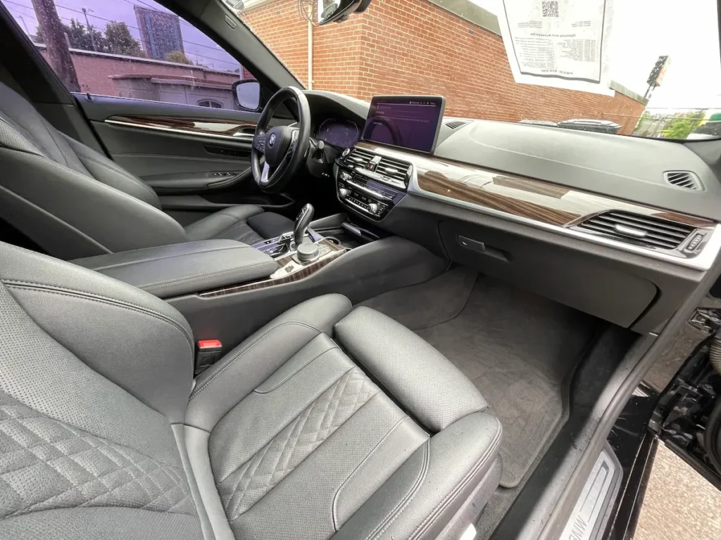 BMW 530i front interior view showing dashboard, wood trim, and center console controls.