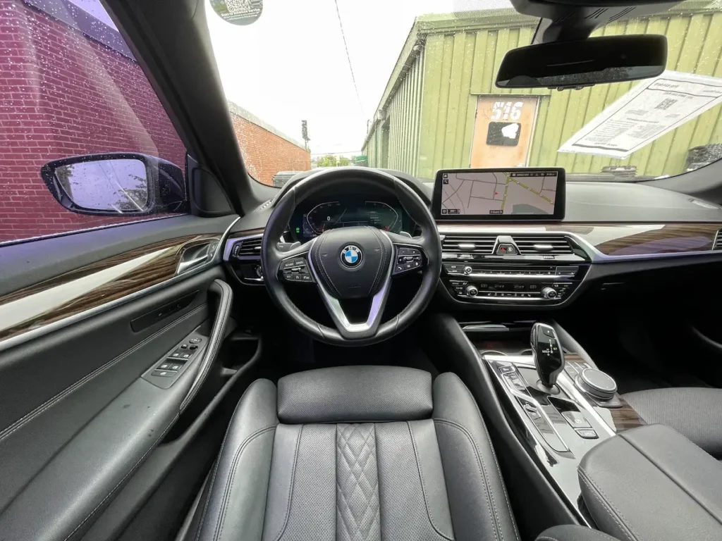 BMW 530i interior showing driver cockpit with steering wheel, iDrive display, and center console.