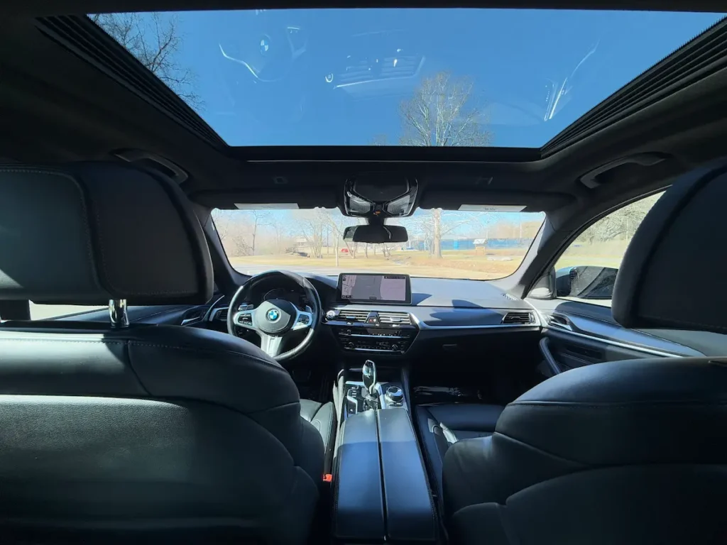 BMW 540i xDrive interior view showing panoramic sunroof and dashboard layout.