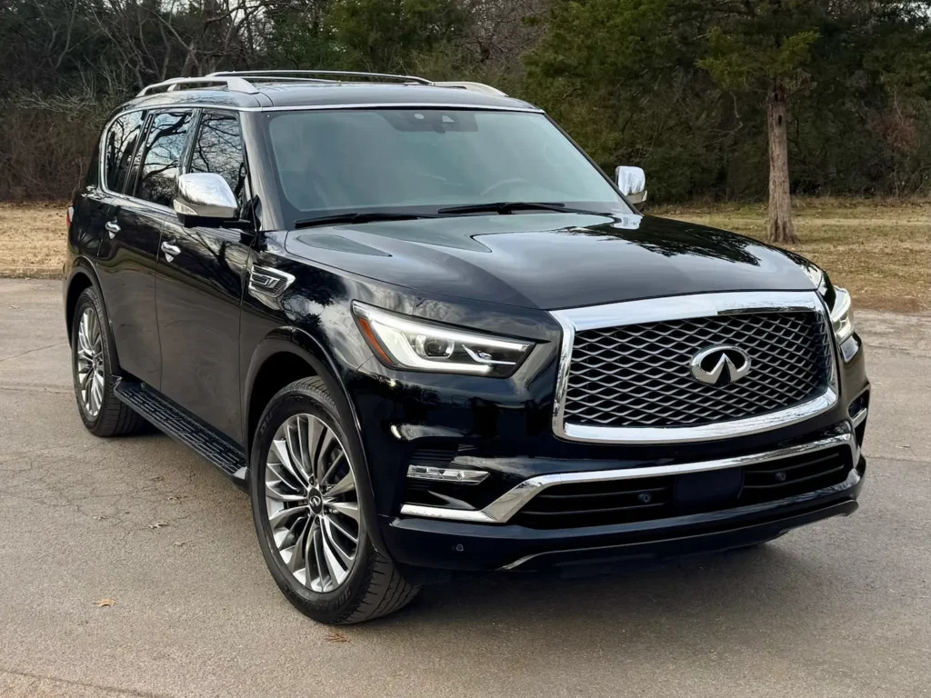 Black 2021 Infiniti QX80 parked outdoors with trees in the background.