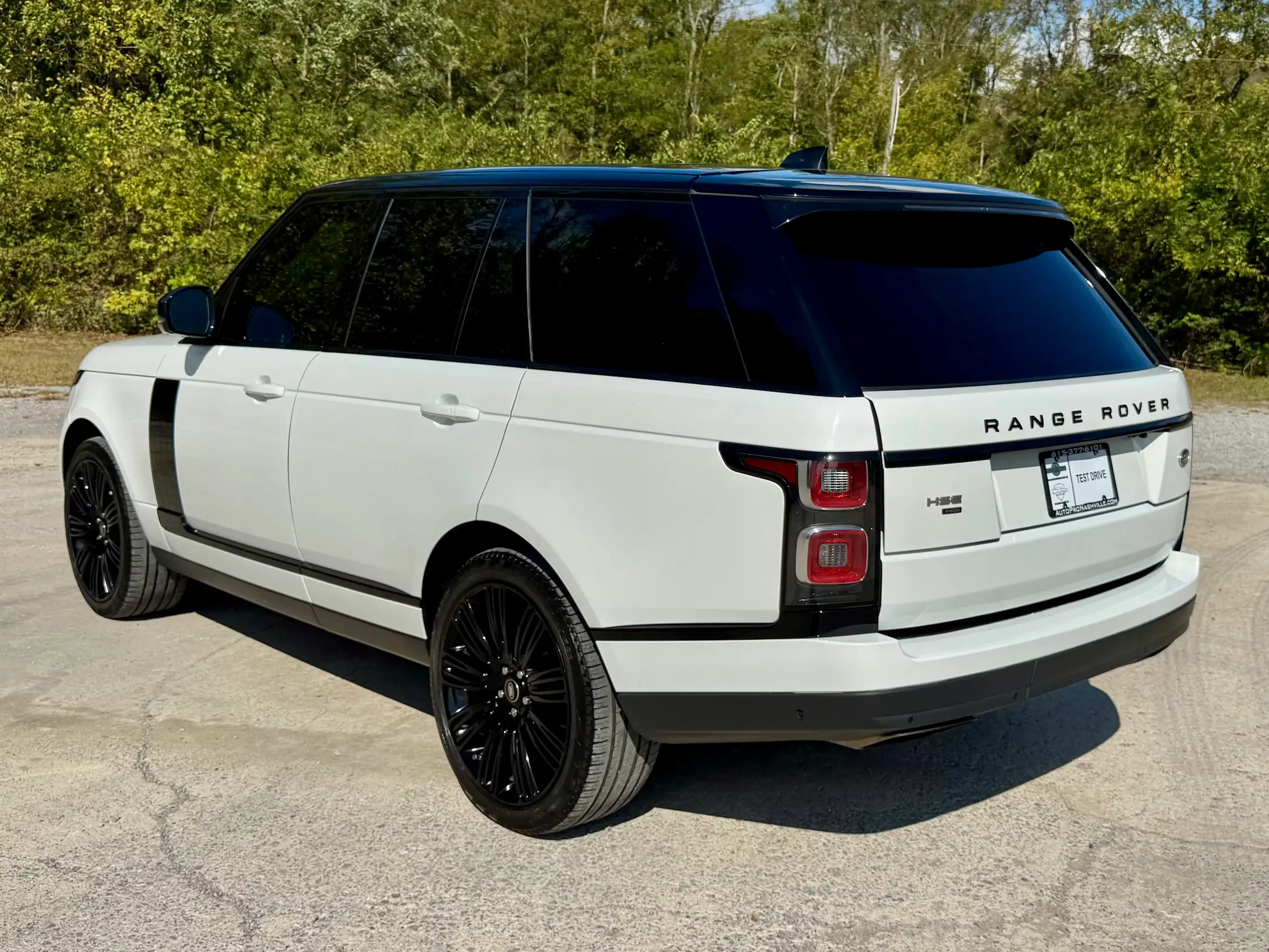 Rear three-quarter view of a white 2021 Range Rover Westminster with a black roof, rear spoiler and black wheels.