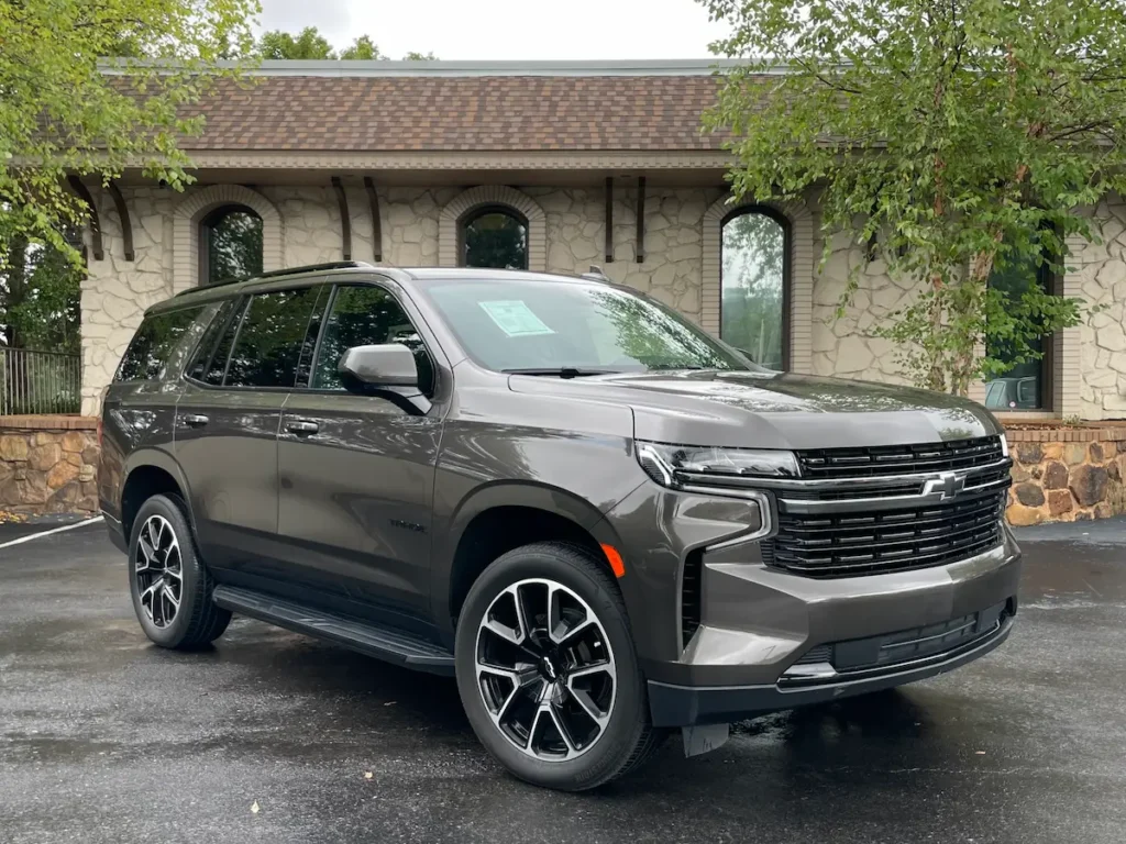 Front and side angle of a 2021 Chevrolet Tahoe RST in dark beige with LED lighting and sport grille.
