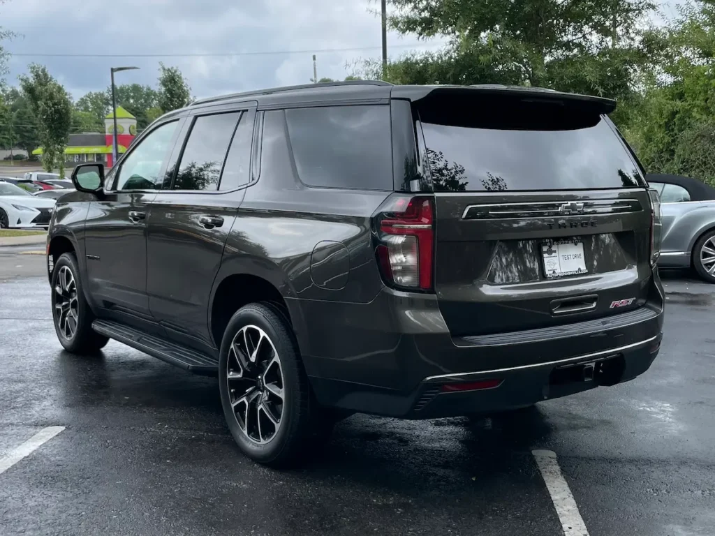 Rear and side angle of a 2021 Chevrolet Tahoe RST in dark beige with black wheels and tinted windows.