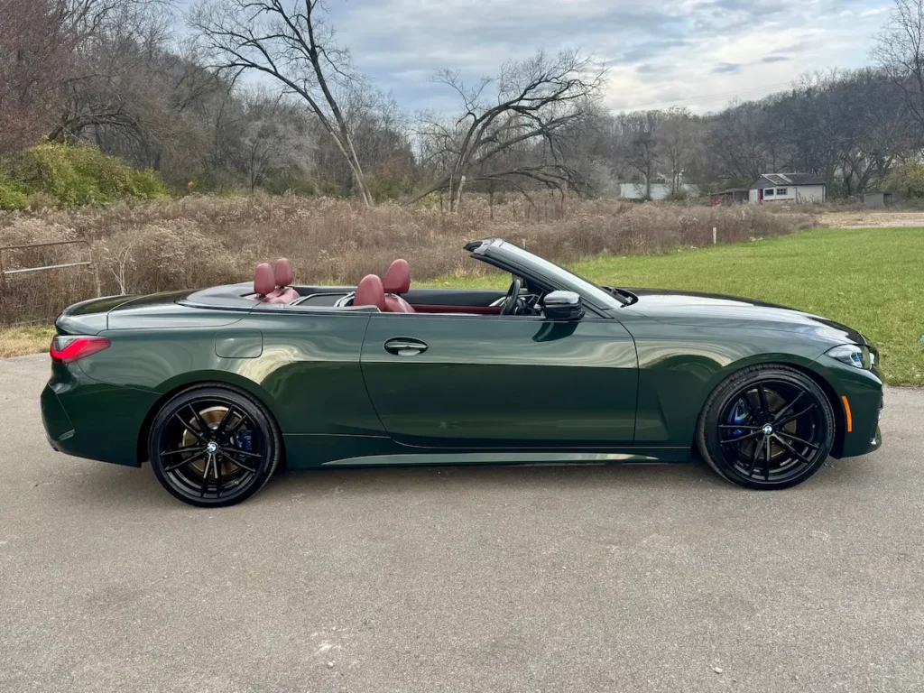 Side profile of 2022 BMW M440i Convertible in green with top down, sporty silhouette.