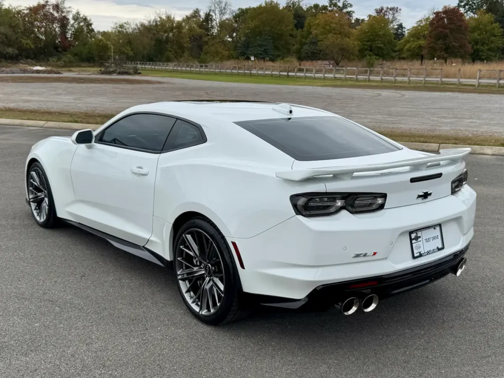 Rear and side view of a 2022 Chevrolet Camaro ZL1 in white with quad exhaust and rear spoiler.