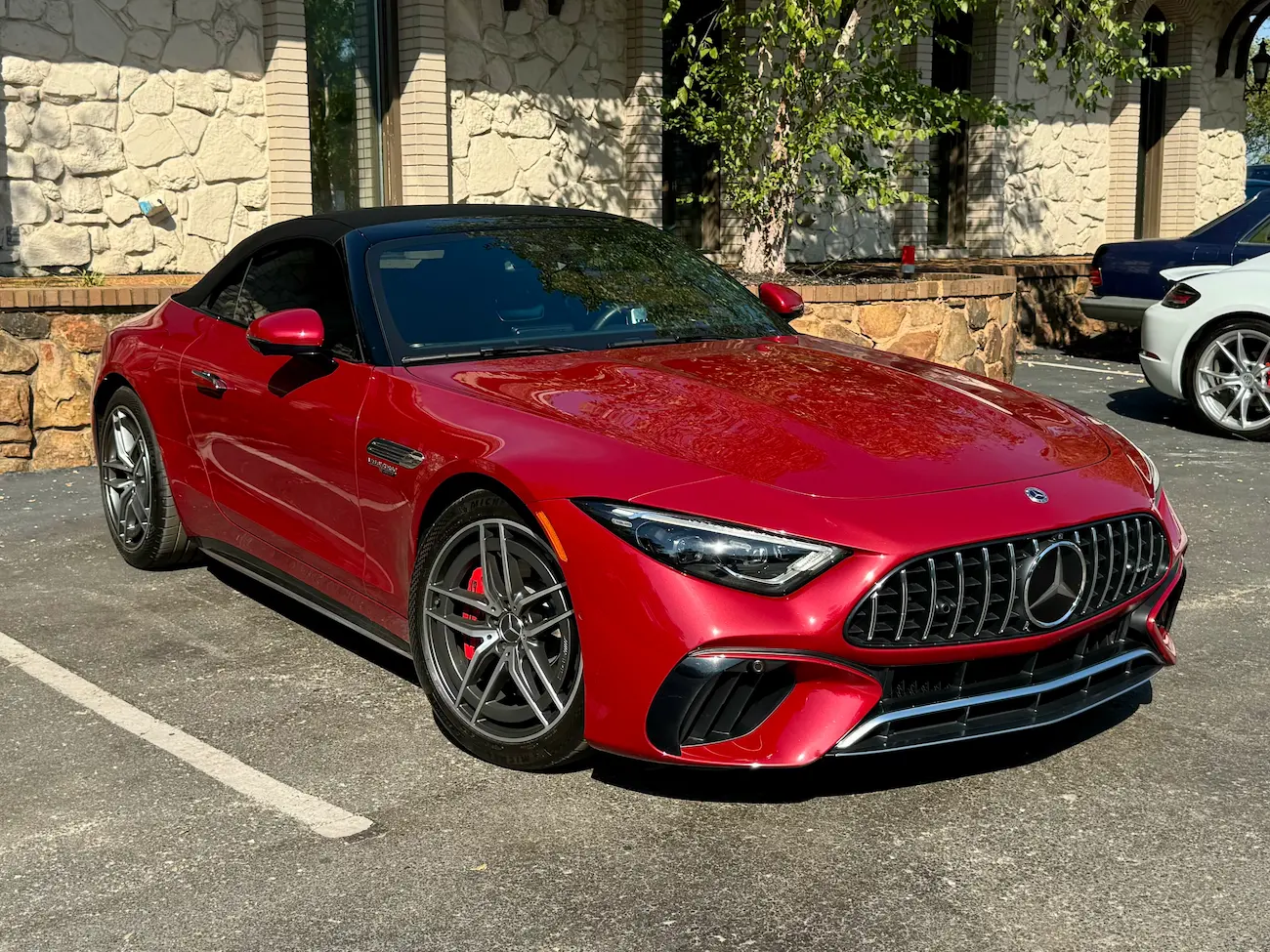 2022 Mercedes-AMG SL55 Roadster in red with black soft top, front view showing AMG grille and sleek headlights.