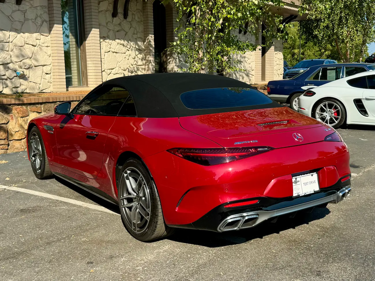 Rear view of a 2022 Mercedes-AMG SL55 Roadster in red, showcasing quad exhausts and sleek tail lights.