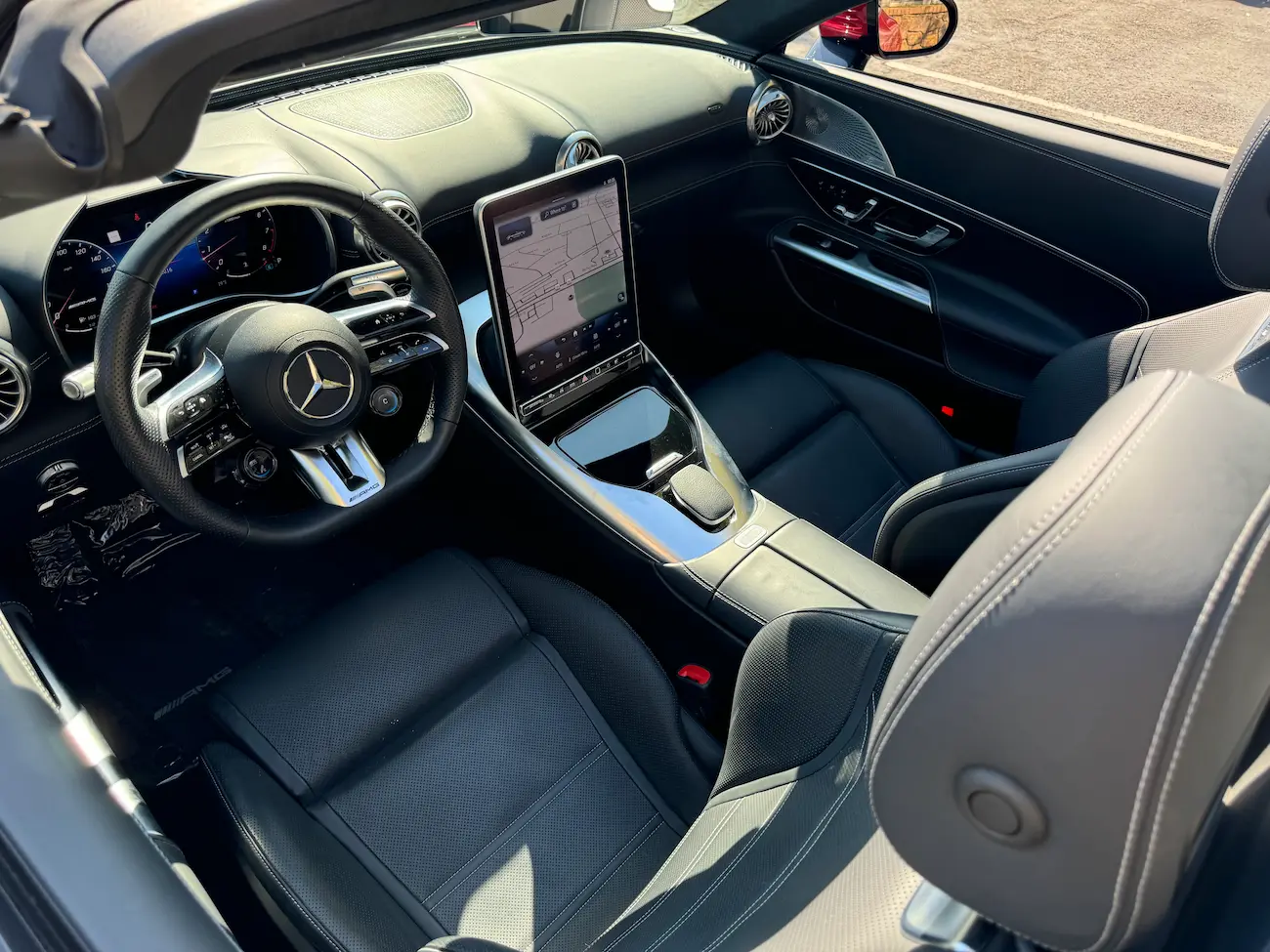 Interior view of the 2022 Mercedes-AMG SL55 Roadster with black leather, AMG steering wheel, and MBUX touchscreen.