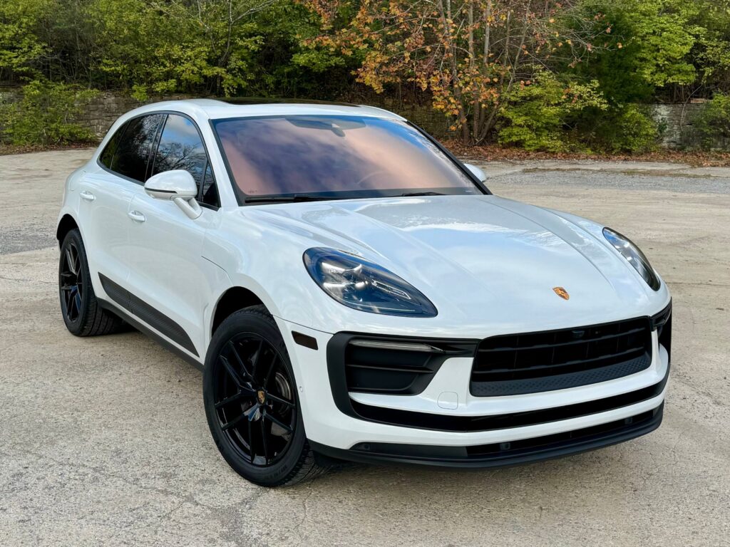 A luxurious white 2022 Porsche Macan captured outdoors, highlighting its elegant front view with LED headlights and the signature Porsche design.