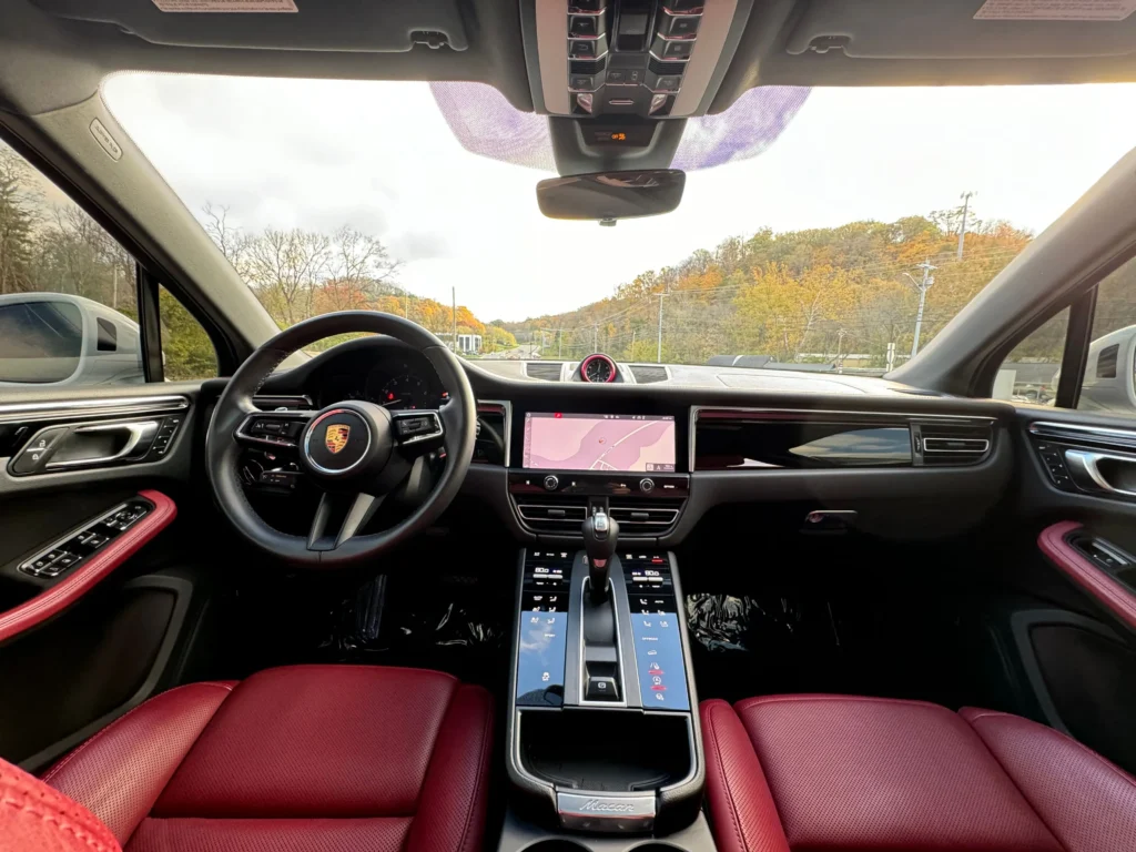 The luxurious interior of a 2022 Porsche Macan with red leather seats and a modern dashboard.