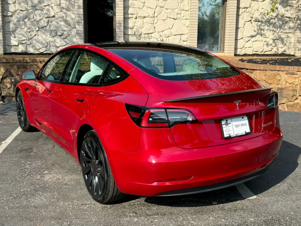 Rear view of red 2022 Tesla Model 3 Performance showing fastback roofline and LED taillights.