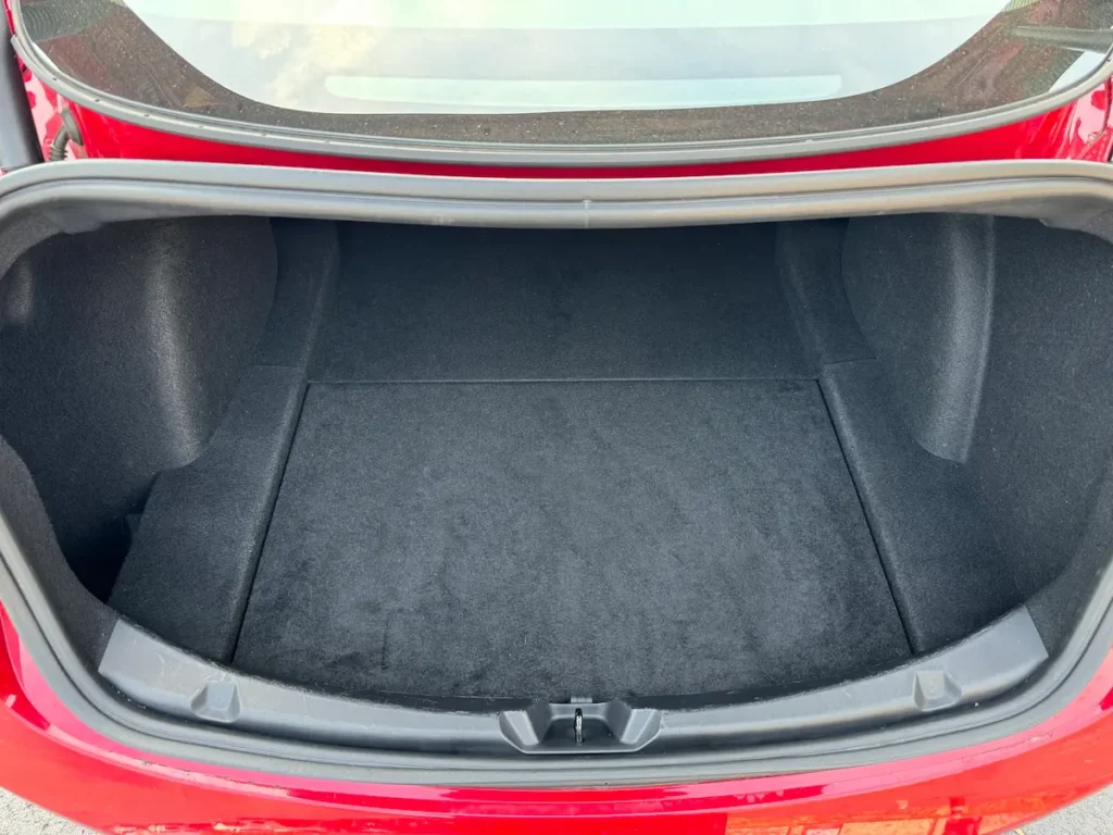 Open trunk of Tesla Model 3 showing flat carpeted cargo area with ample storage capacity.
