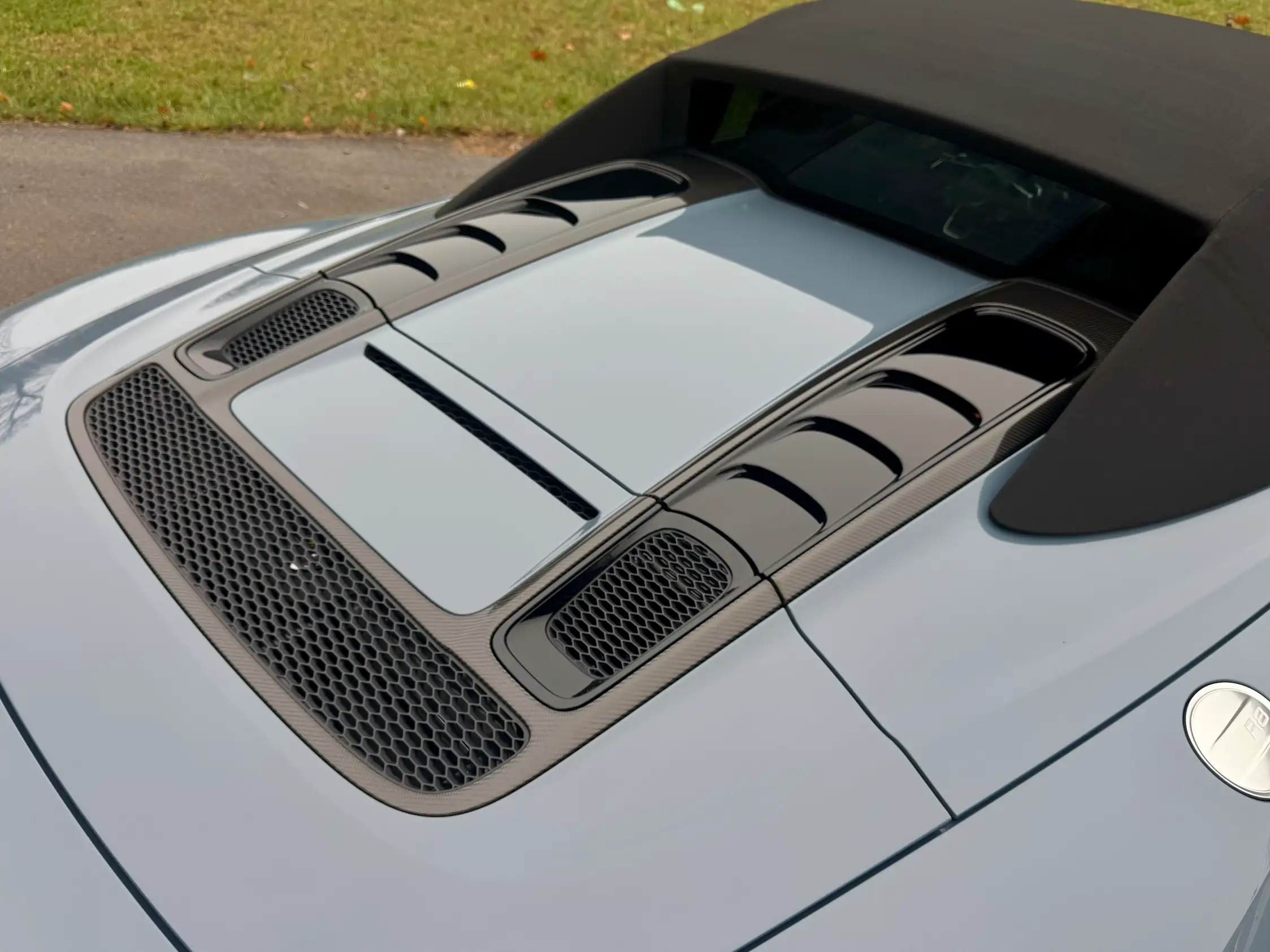 Close-up of the blue 2023 Audi R8 Spyder’s rear deck, showing black vents, mesh grilles, and the closed soft top.