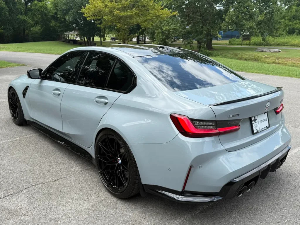2023 BMW M3 grey rear three-quarter view highlighting quad exhaust and LED tail lights.
