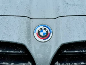 BMW M badge on hood with water droplets highlighting performance branding