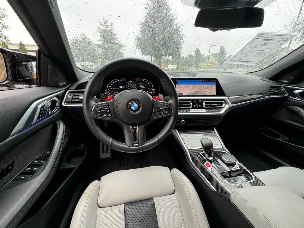 BMW M4 driver cockpit interior with digital gauges, M steering wheel and infotainment screen