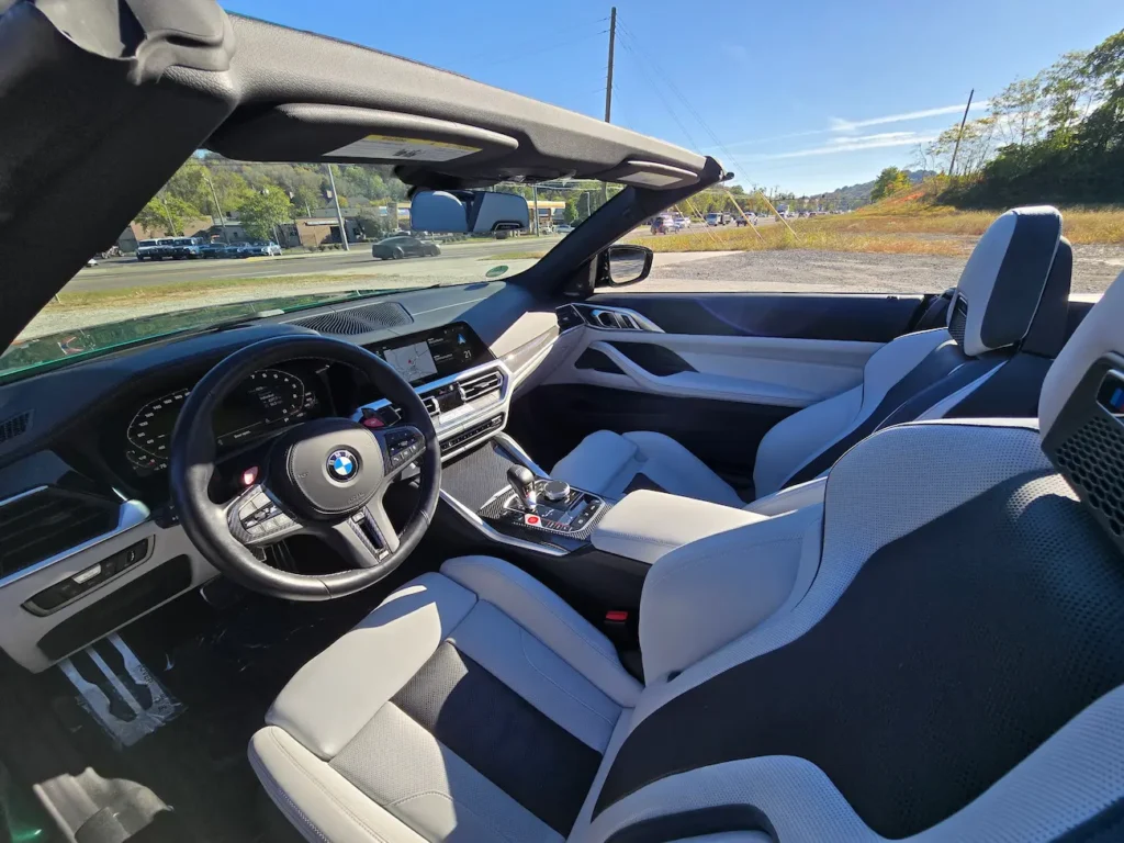 Interior of 2023 BMW M4 Competition Convertible showing two-tone sport seats and digital cockpit.