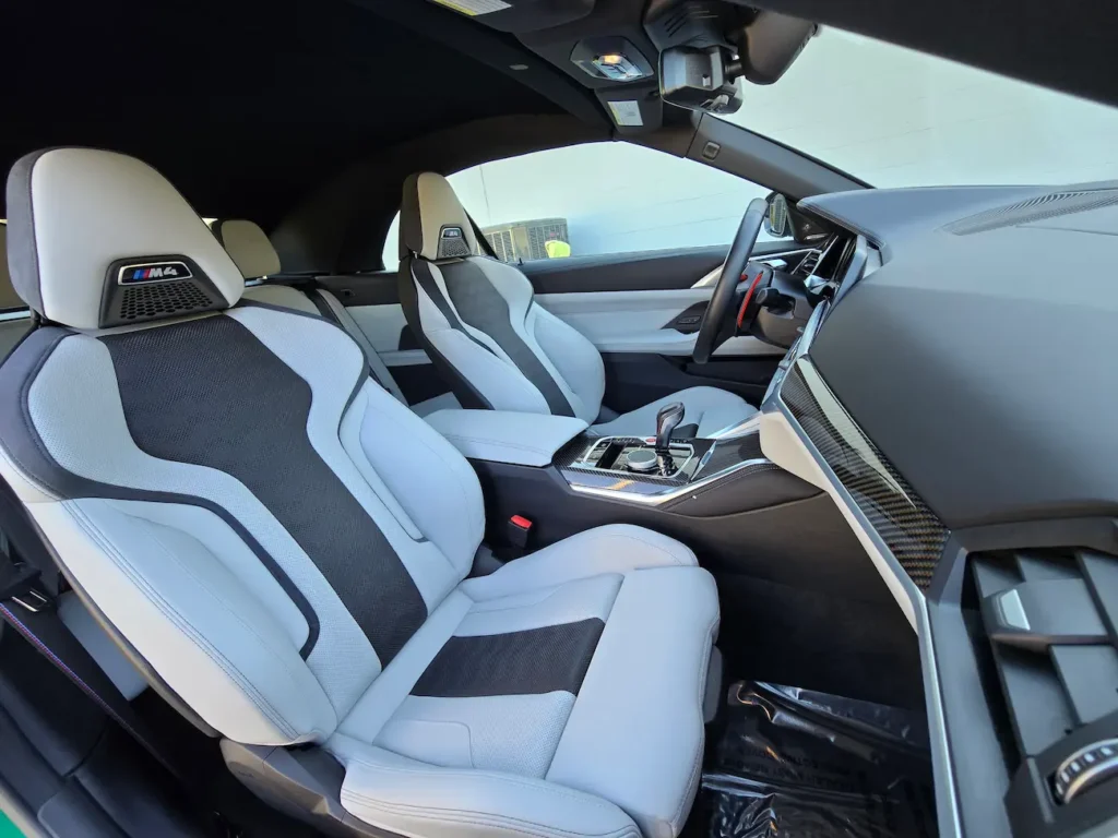 Passenger-side view of the 2023 BMW M4 Competition Convertible interior with carbon fiber trim and M seats.