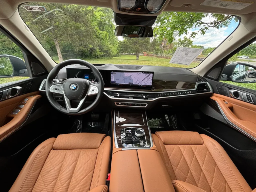 2023 BMW X7 xDrive40i front interior with cognac leather, curved display, and wood trim