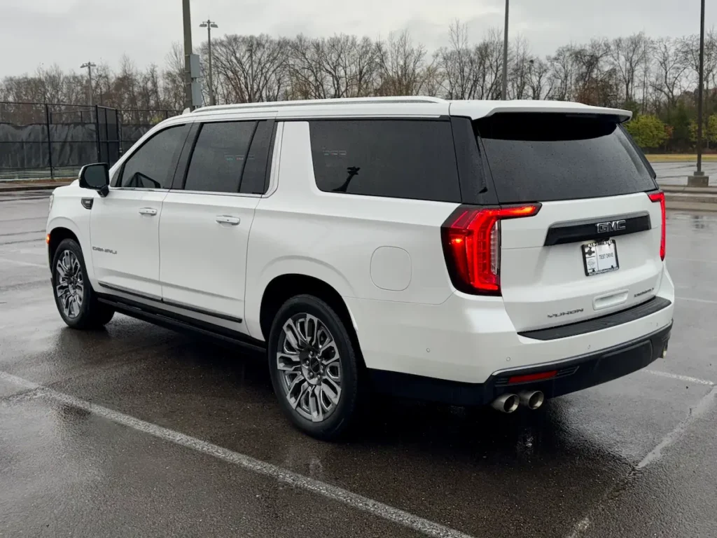 Rear exterior view of a white 2023 GMC Yukon XL Denali showcasing taillights and extended body.