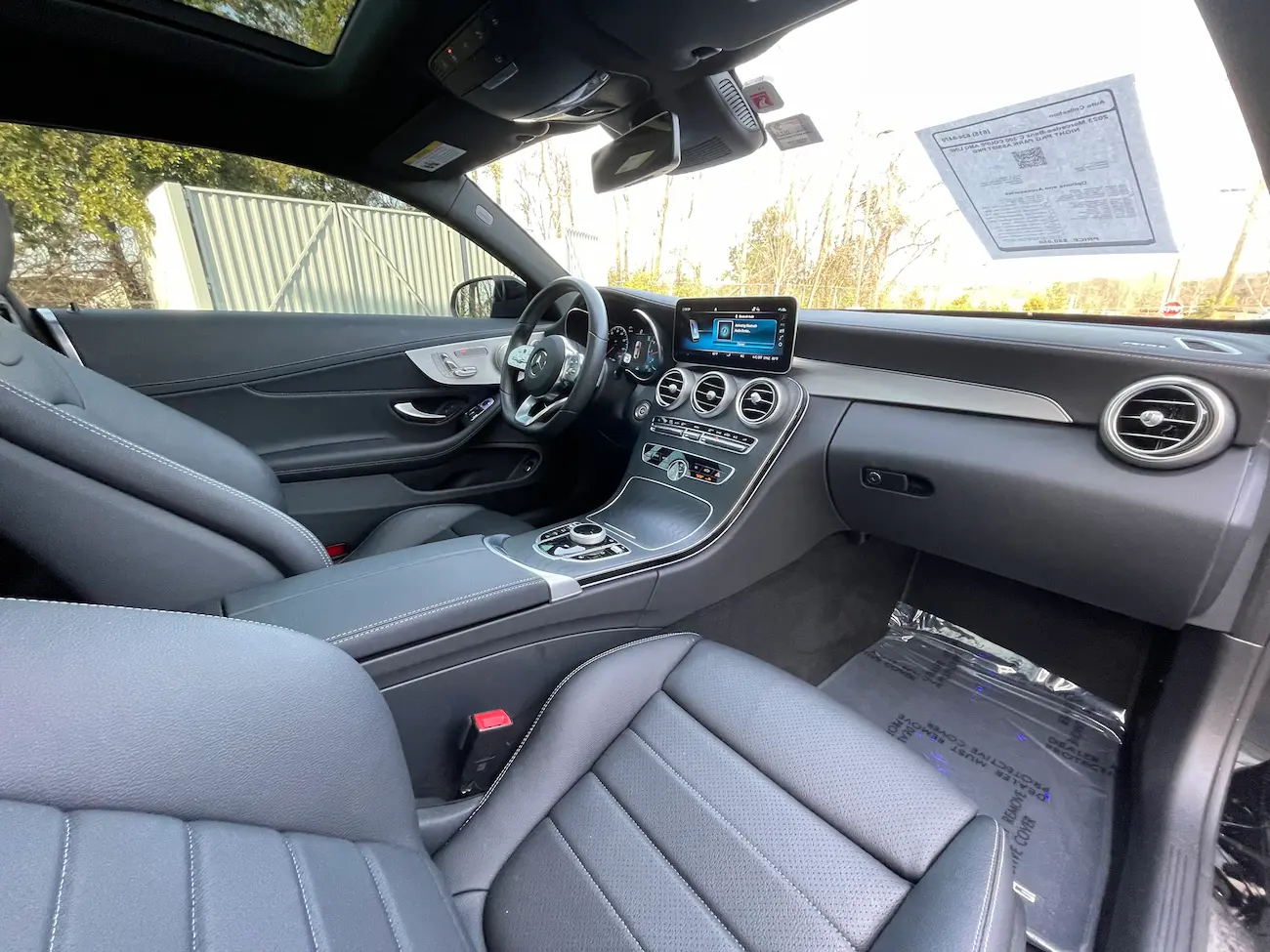 Center console of 2023 Mercedes-Benz C 300 Coupe highlighting infotainment screen and ambient lighting.
