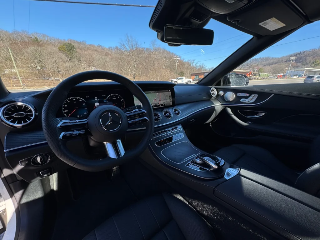Interior of 2023 Mercedes-Benz E 450 Cabriolet featuring black leather upholstery, digital cockpit, and MBUX infotainment display.