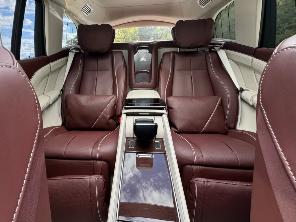 Rear interior of 2023 Mercedes-Benz GLS 600 Maybach with reclining brown Nappa leather seats, central control console, and Maybach logo detailing.