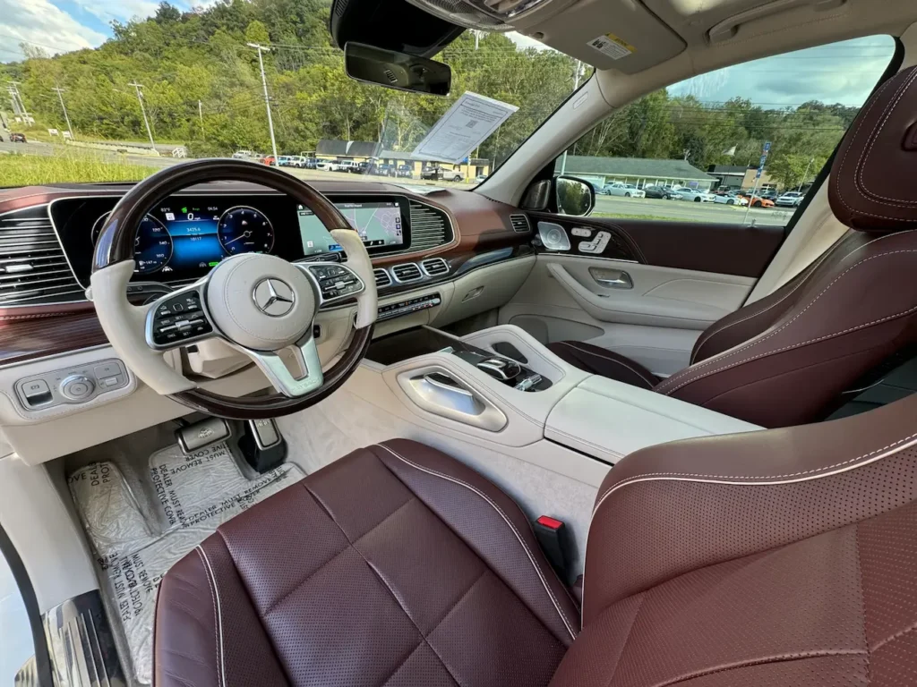 Dashboard and steering of 2023 Mercedes-Benz GLS 600 Maybach featuring digital driver display, brown leather interior, and ambient lighting.