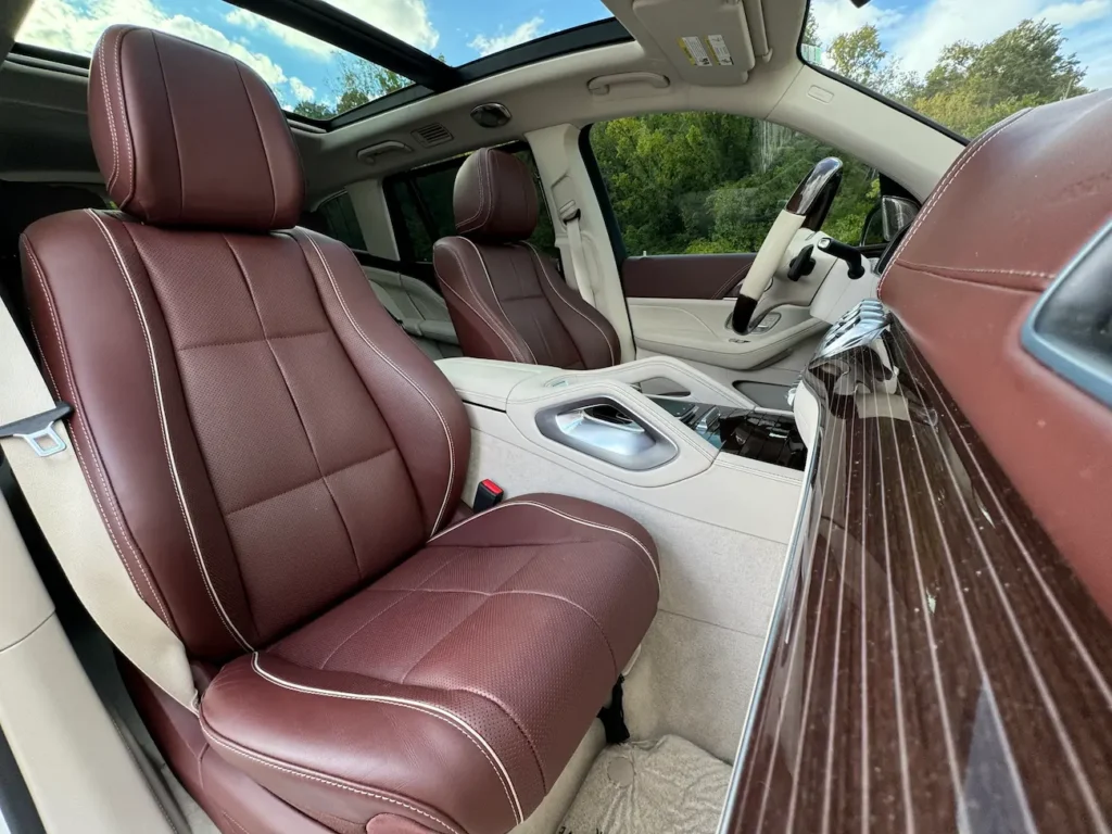 Front seats of 2023 Mercedes-Benz GLS 600 Maybach with two-tone brown and beige leather upholstery, panoramic sunroof, and fine wood trim.