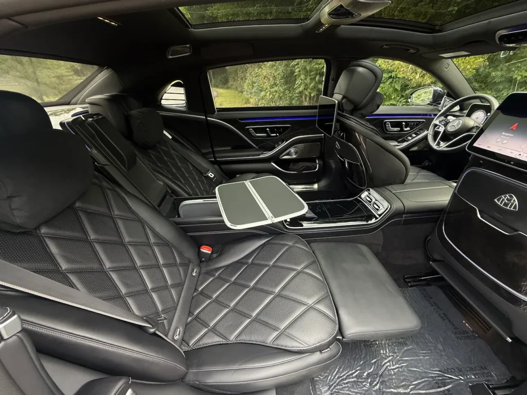 Rear seating of the 2023 Mercedes-Benz S580 Maybach with executive lounge chairs, tray tables, and dual screens.