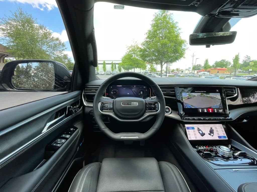 Driver's view of the 2023 Jeep Grand Wagoneer black interior, featuring a sleek dashboard, digital displays, and a panoramic view.