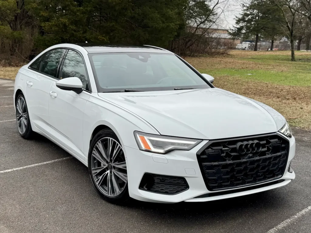 Front exterior view of the 2024 Audi A6 in white, featuring a black Singleframe® grille and LED headlights at AutoPro Nashville.