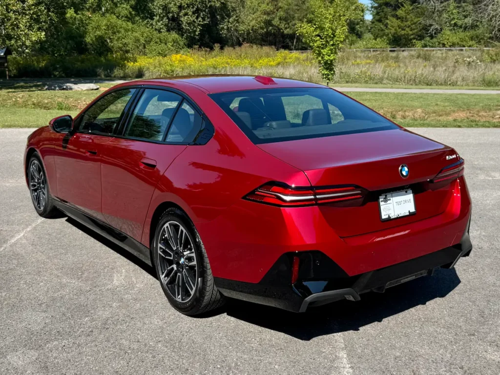 Rear view of a red 2024 BMW 530i featuring sculpted LED taillights and sporty bumper.
